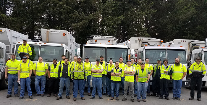 Mason County Garbage & Recycling drivers standing in front of their fleet of trucks