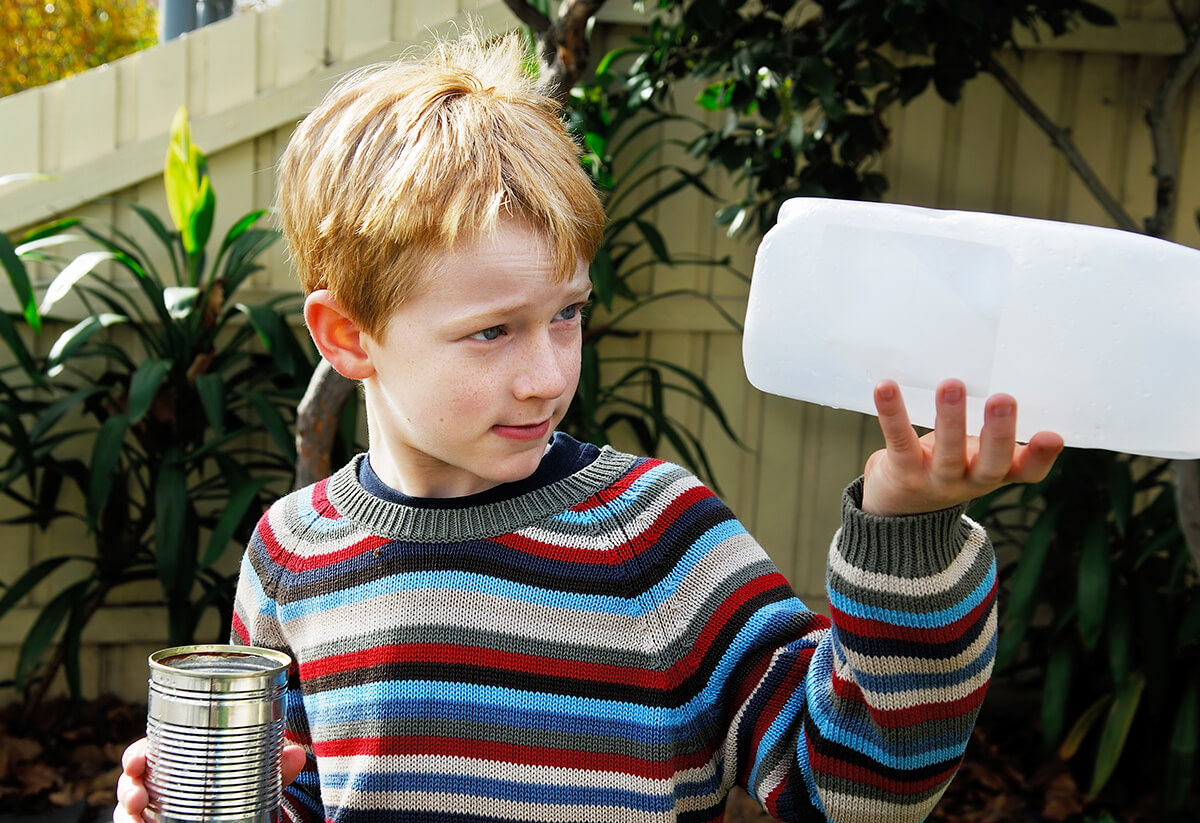 Picture of a young boy holding recyclable items.