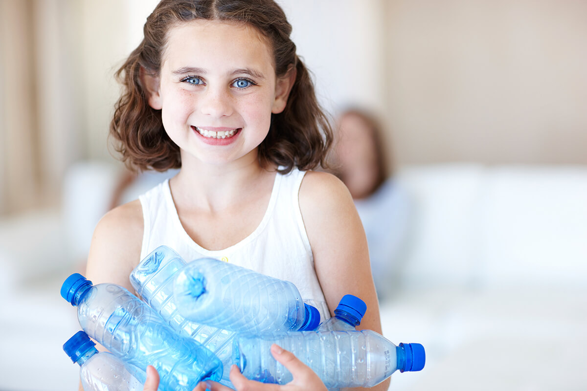 Picture of a little girl holding plastic water bottles.